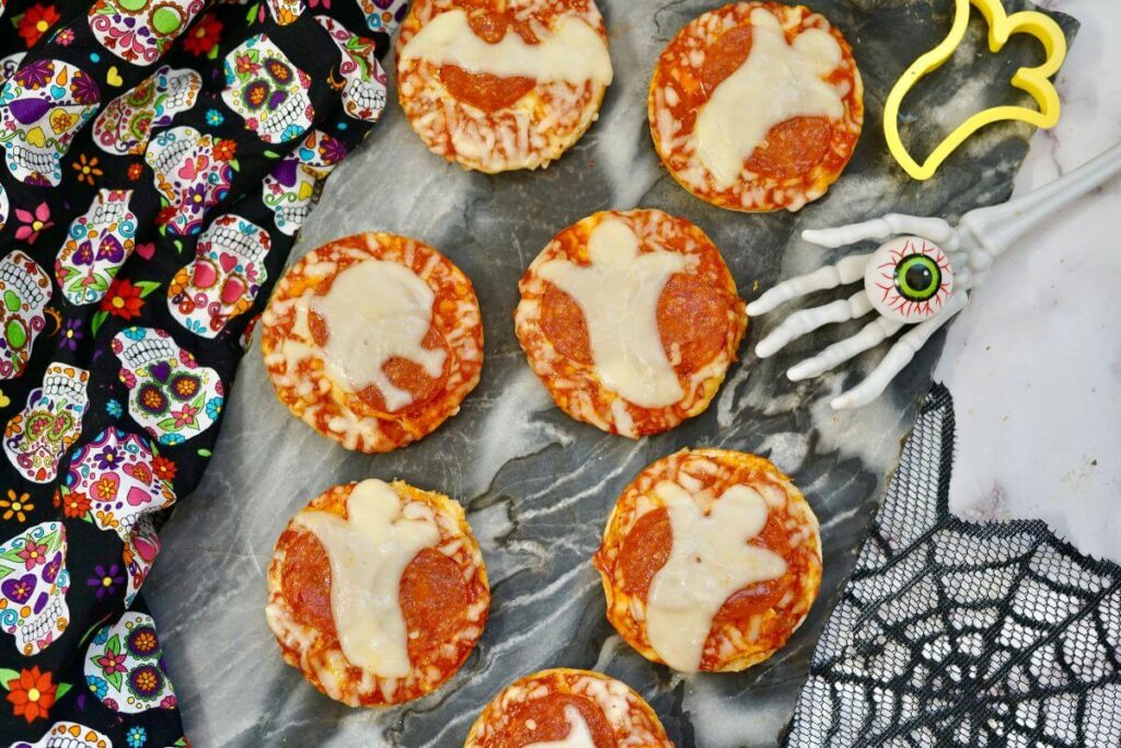 Mini Halloween Pizzas on tray with spider web and skeleton hand