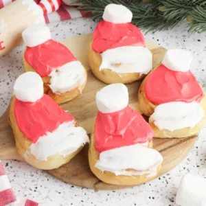 Featured images of Santa Cinnamon Rolls sitting on a wooden block.
