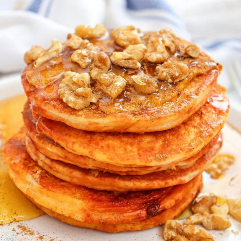 a plate of fluffy pumpkin pancakes with maple syrup and nuts on top