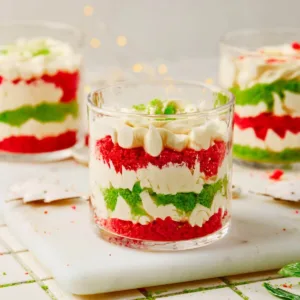 Mini Christmas Trifles with layers of green cake, red cake, and white cream cheese frosting