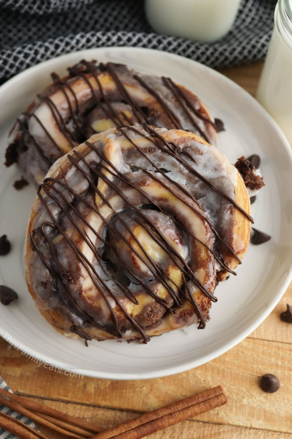 a plate with 2 brownie cinnamon rolls with chocolate chips scattered around