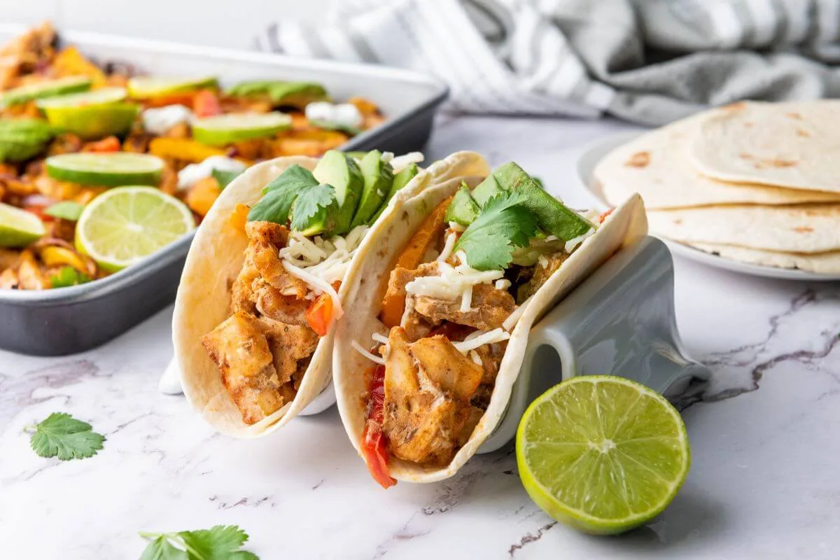 Two chicken fajitas being served in tortilla shells. 