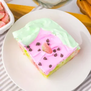 Slice of watermelon poke cake on a plate.