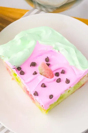 Slice of watermelon poke cake on a plate.