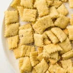 Plate of sourdough crackers with herbs and sea salt on a white plate.